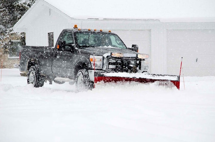 A truck uses a snow plow to remove snow out of the streets