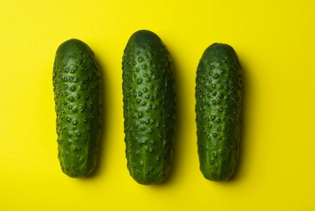 Three cucumbers on top of yellow table