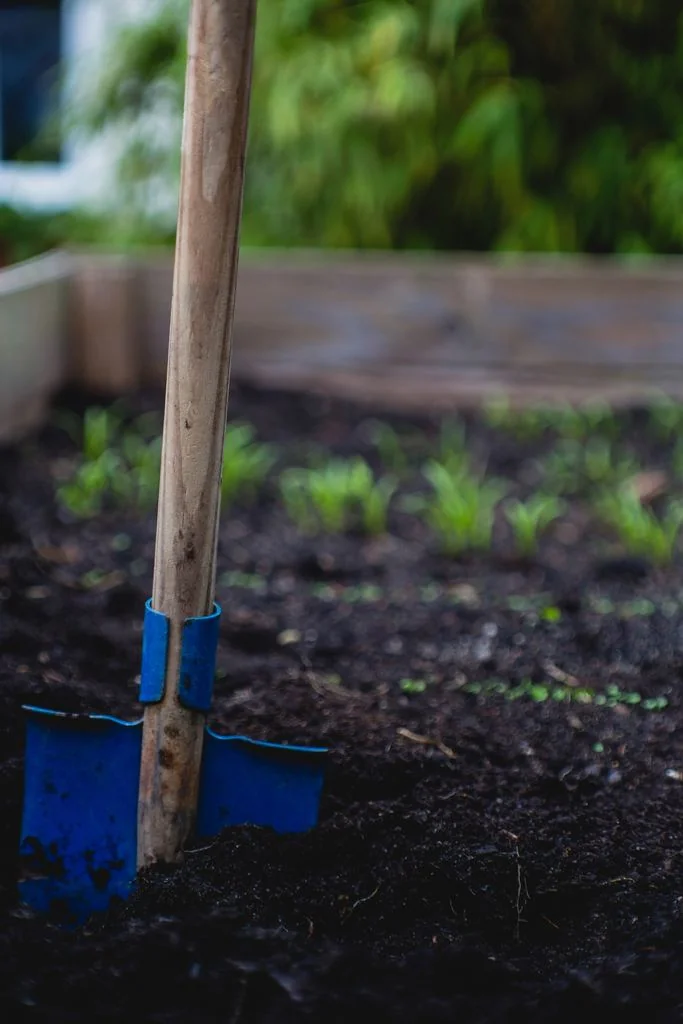 a shovel on a plant box used for square foot garden spacing