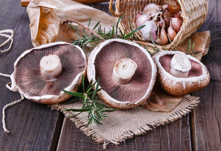 Portobello Mushrooms with rosemary and onions on wooden table